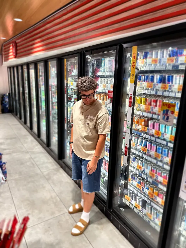 Will Smith standing in a corner store aisle in white socks and sandals