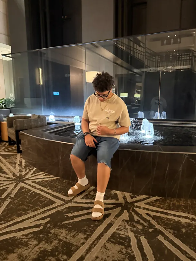 Will Smith sitting on the edge of an indoor fountain in sandals and socks