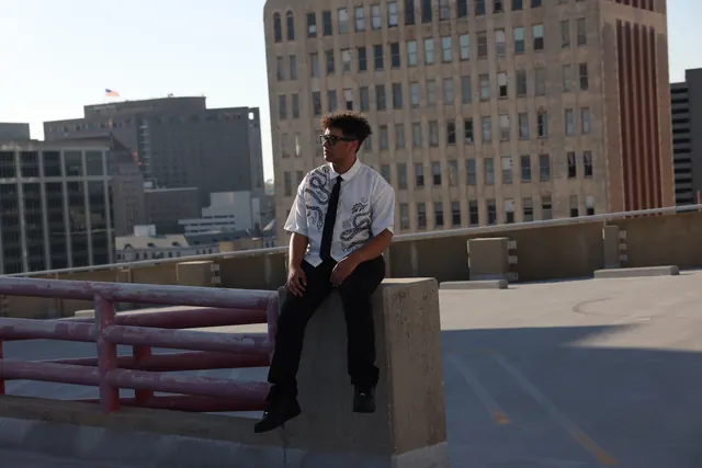 Will Smith seated on a concrete barrier on a rooftop parking deck