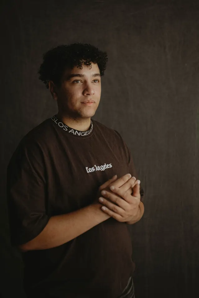 Studio portrait of Will Smith in a brown Los Angeles tee, hands clasped